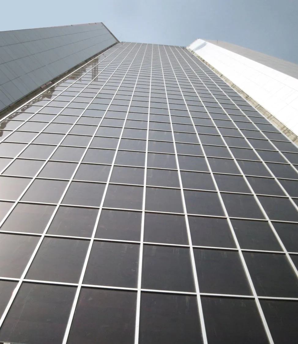 Looking up a glass façade with integrated photovoltaic panels kept clean by the iku® system